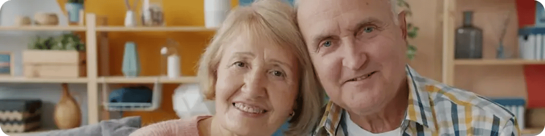 Pareja de adultos mayores sonriendo juntos en su casa.