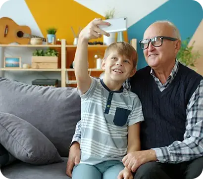 Adulto mayor y niño tomándose una selfie sentados en un sofá.