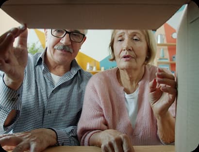 Pareja de adultos mayores revisando juntos el contenido de una caja de cartón en casa