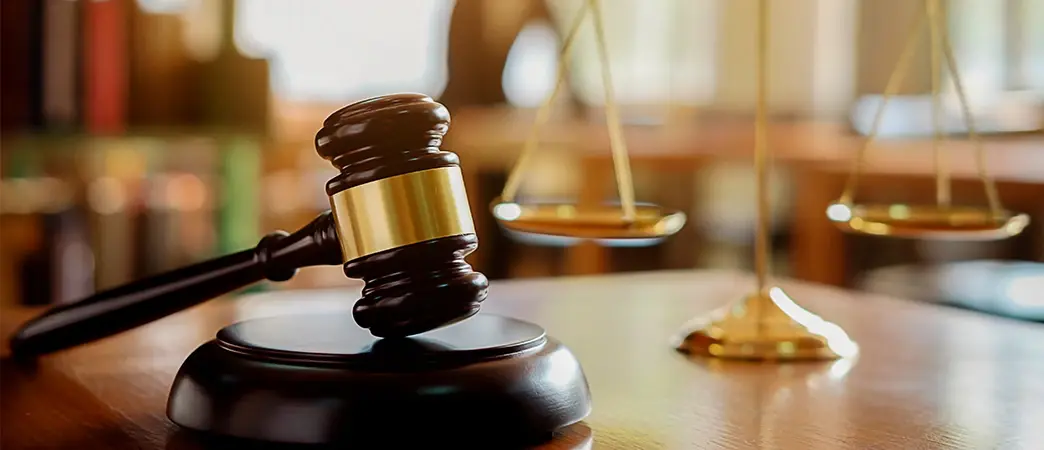 Mazo de juez sobre una mesa junto a una balanza dorada de la justicia