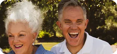 Pareja de adultos mayores riendo al aire libre.