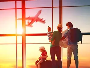 Familia observando un avión desde la ventana del aeropuerto durante el atardecer.