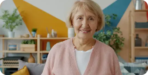 Mujer adulta mayor sonriendo en la sala de su casa.
