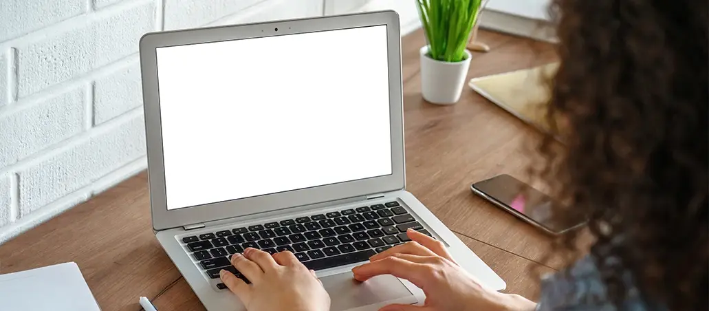 Persona usando una computadora portátil con pantalla en blanco sobre un escritorio
