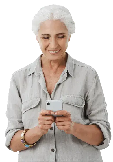 Mujer adulta mayor sonriendo mientras escribe en su teléfono celular.