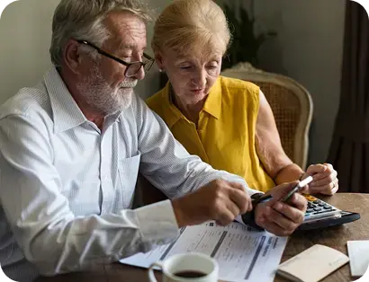 Pareja de adultos mayores revisando documentos en casa.