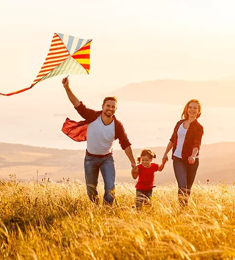 Familia volando una cometa en un campo al atardecer